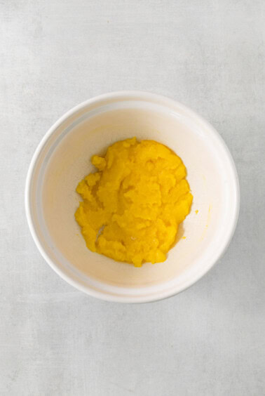 a white bowl filled with yellow food on top of a table.