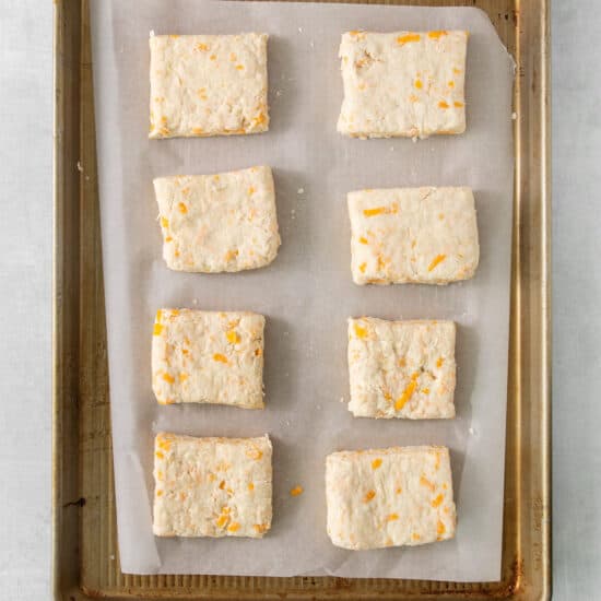 a baking sheet with a tray of cheese biscuits on it.