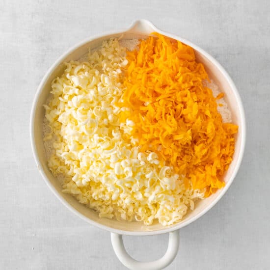shredded cheese and carrots in a white bowl.