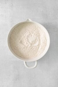 flour in a white bowl on a gray background.