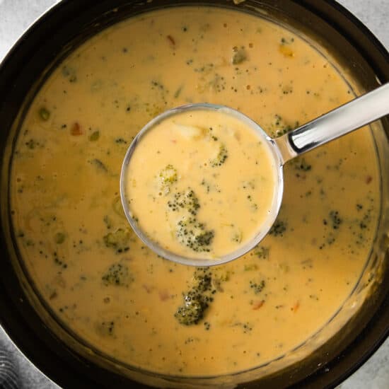 a bowl of broccoli and cheese soup with a spoon.