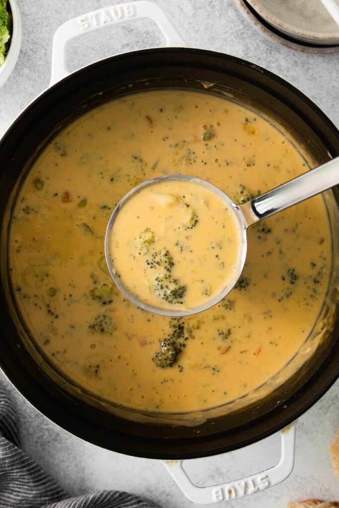 a bowl of broccoli and cheese soup with a spoon.