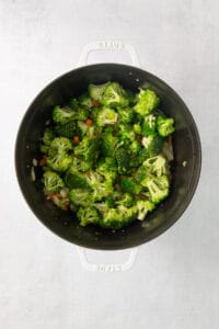 a pan filled with broccoli and carrots on a white surface.