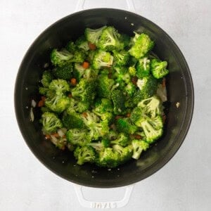 a pan filled with broccoli and carrots on a white surface.