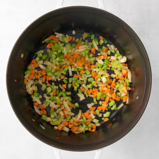 a pan with vegetables in it on a white surface.