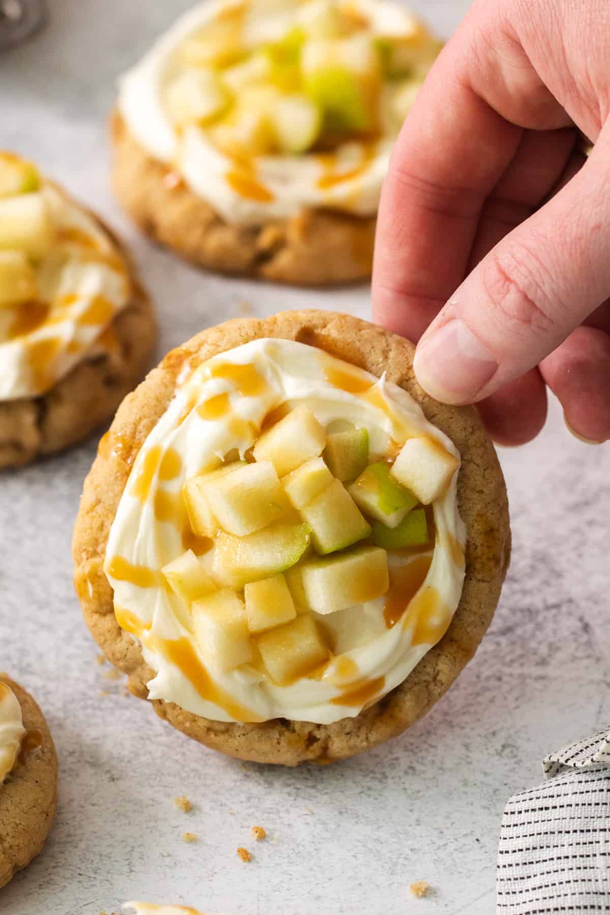 a person picking up a cookie with apples on top.