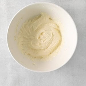 a white bowl filled with white frosting on top of a table.