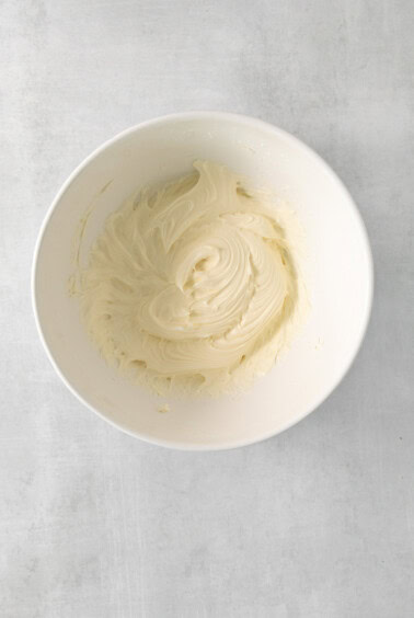 a white bowl filled with white frosting on top of a table.