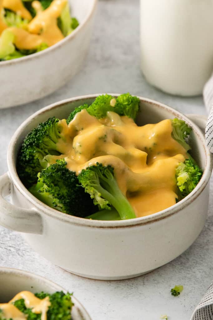 a bowl of broccoli covered in cheese sauce.
