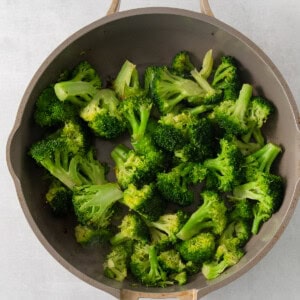 a pan filled with broccoli on top of a table.
