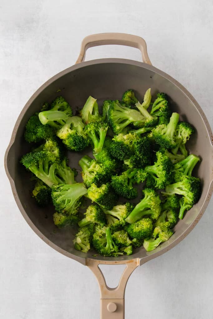 a pan filled with broccoli on top of a table.