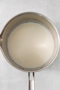 a metal bowl with a handle on a white wall.