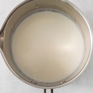 a metal bowl with a handle on a white wall.