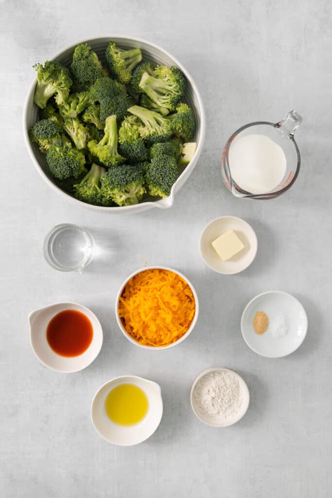 a bowl of broccoli and other ingredients on a table.