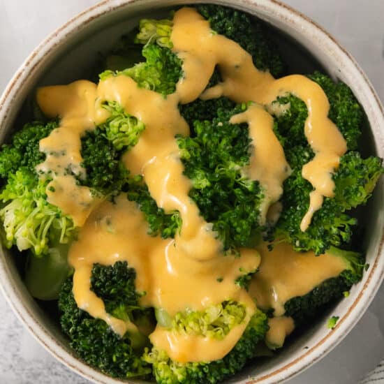 a bowl filled with broccoli covered in cheese.