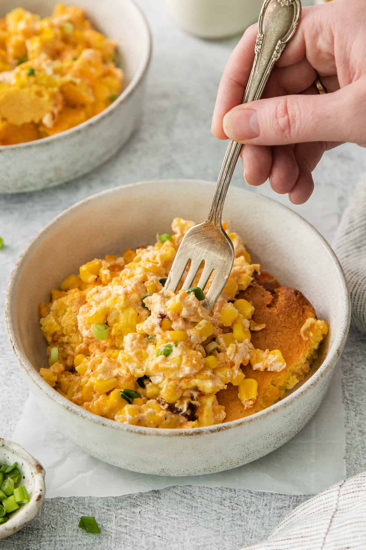 a person holding a fork in a bowl of food.