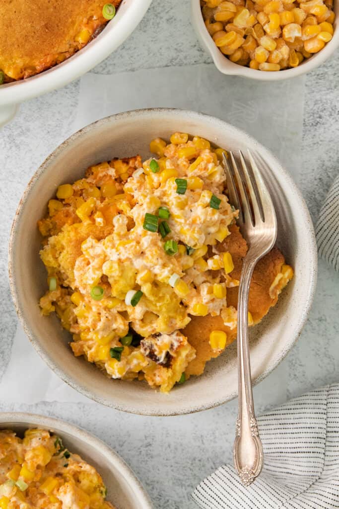 a bowl of corn casserole with a fork in it.