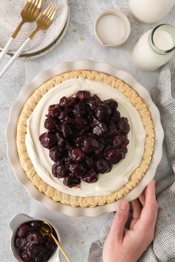 a person holding a pie on a table.