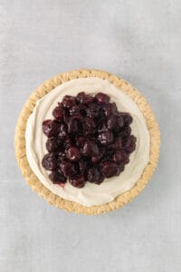 a pie topped with whipped cream and cherries.