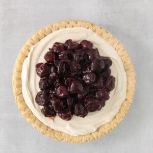 a pie topped with whipped cream and cherries.