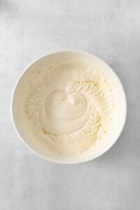 a white bowl filled with white frosting on top of a table.