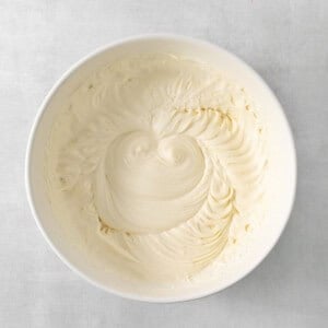 a white bowl filled with white frosting on top of a table.