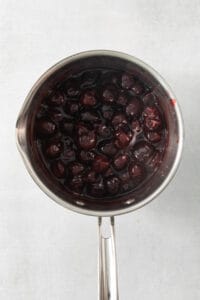 a pot filled with a liquid filled with cherries.