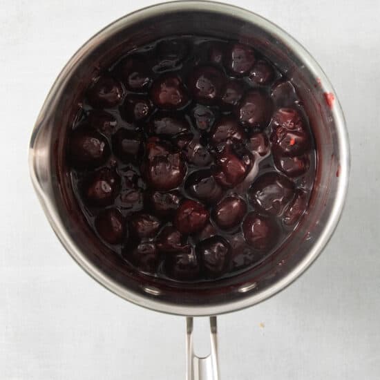 a pot filled with a liquid filled with cherries.