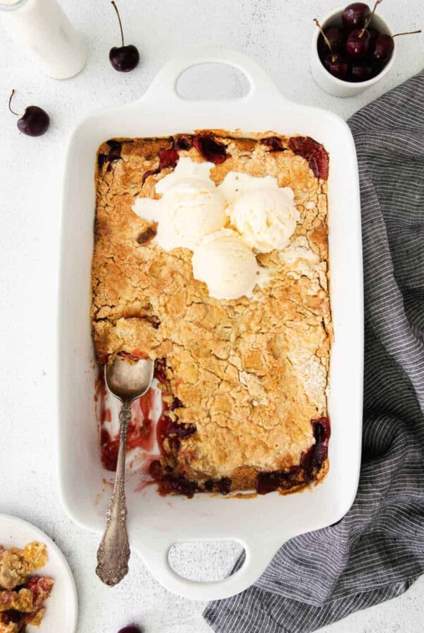 A cherry cobbler with ice cream on top, served in a dish.