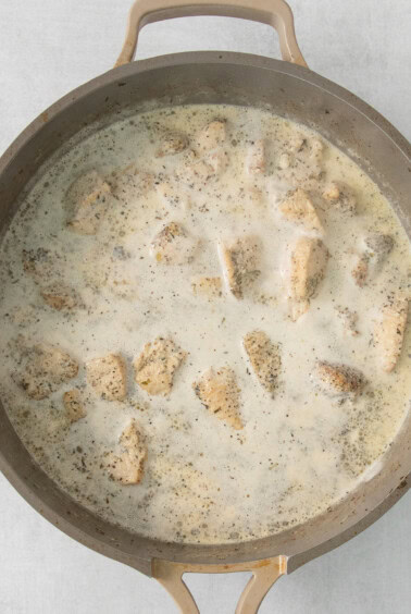 chicken in cream sauce in a skillet.