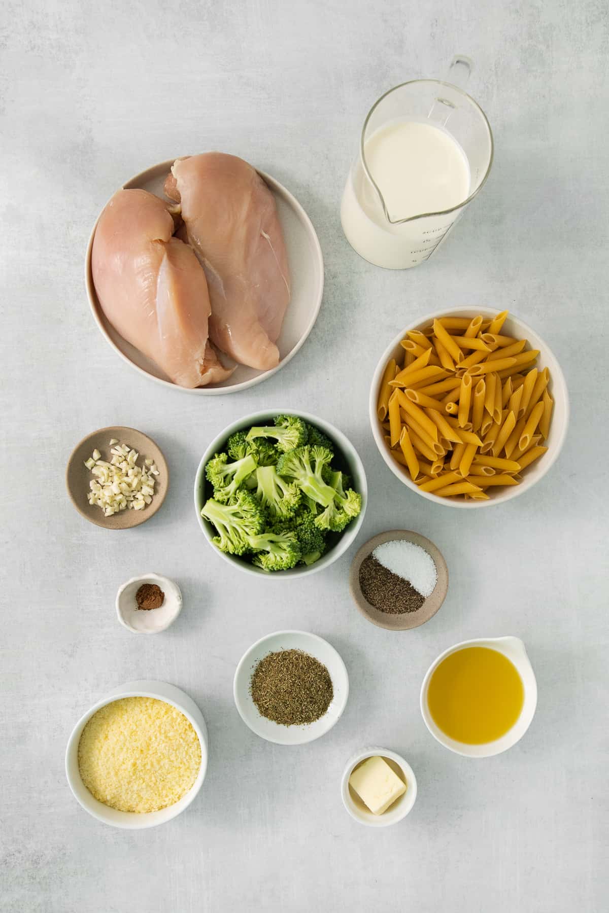 chicken, broccoli, milk and other ingredients on a grey background.