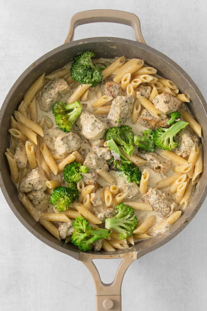 a pan of pasta with broccoli and chicken.