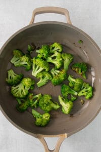 a pan filled with broccoli on top of a table.