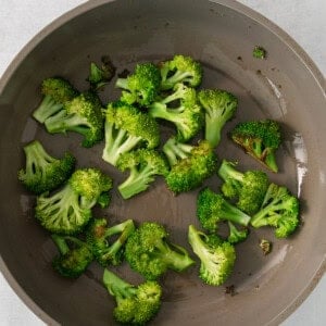 a pan filled with broccoli on top of a table.