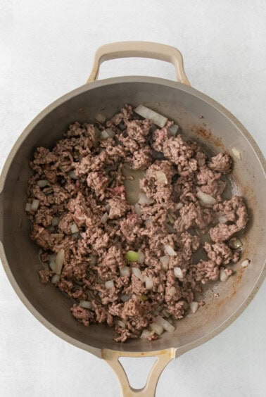 a skillet filled with ground beef and onions.