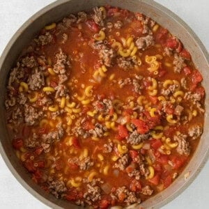 a skillet full of meat and pasta in a white pan.