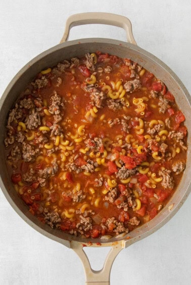 a skillet full of meat and pasta in a white pan.