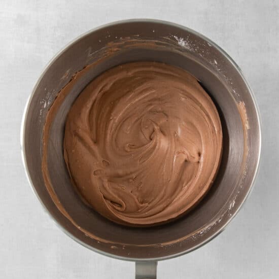 a metal bowl with a chocolate frosting inside of it.