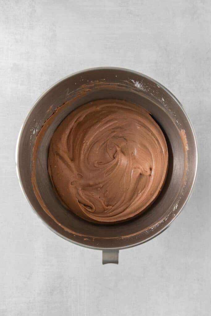 a metal bowl with a chocolate frosting inside of it.