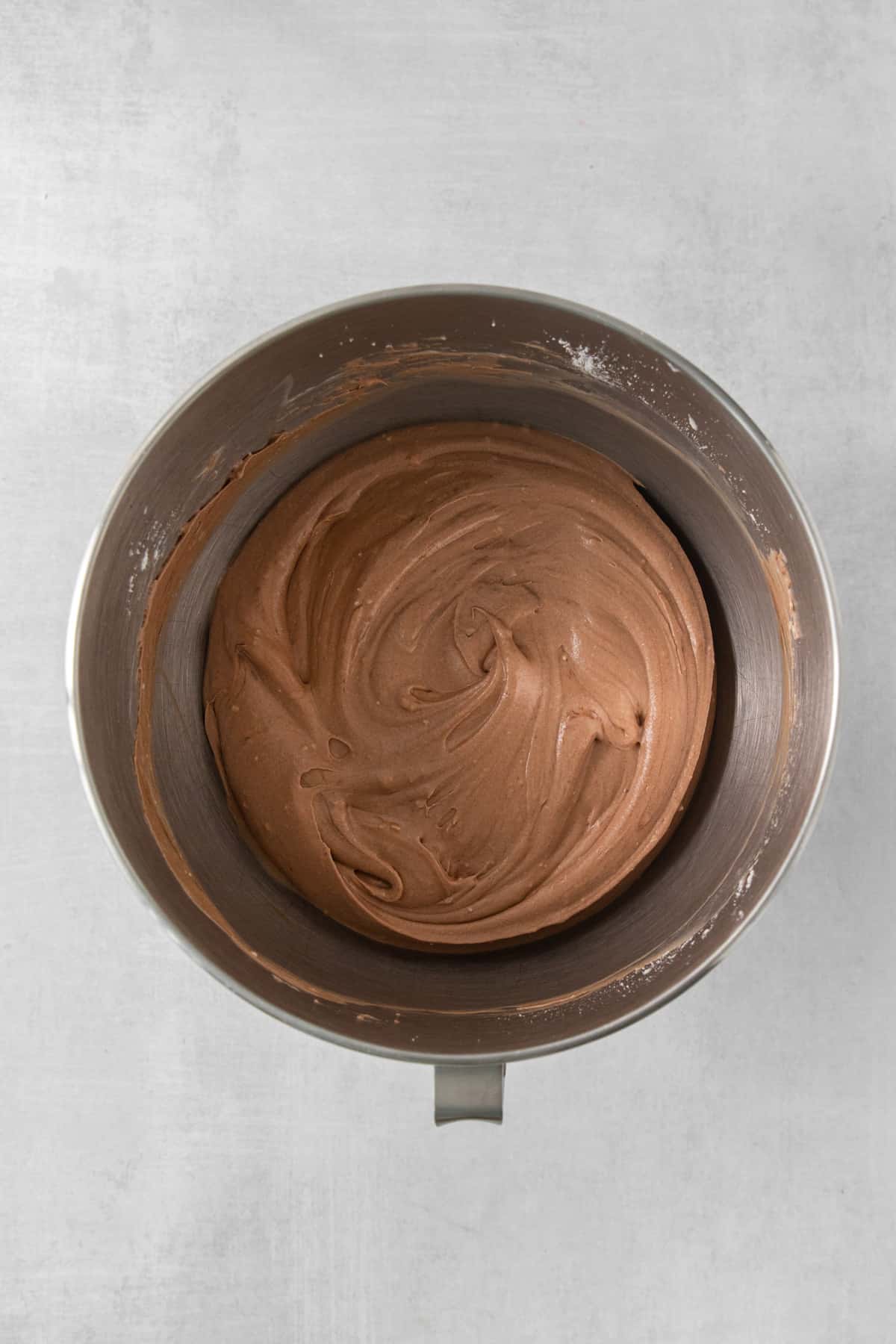 a metal bowl with a chocolate frosting inside of it.