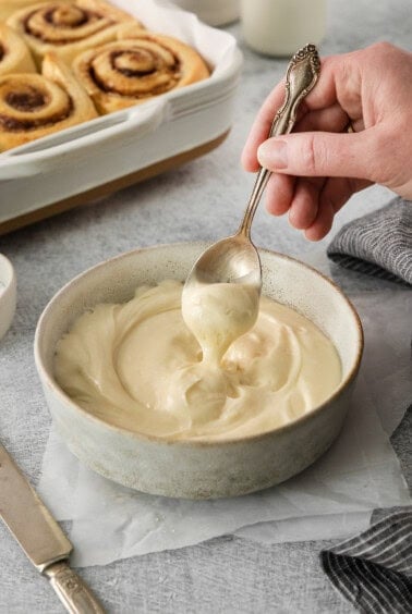 a person spoons a spoonful of cream in a bowl.
