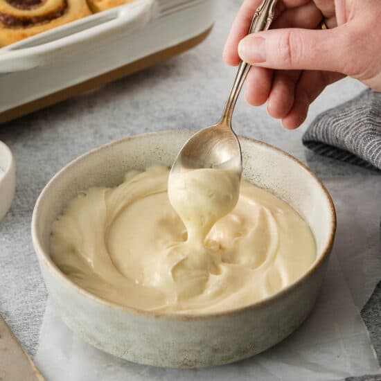 a person spoons a spoonful of cream in a bowl.