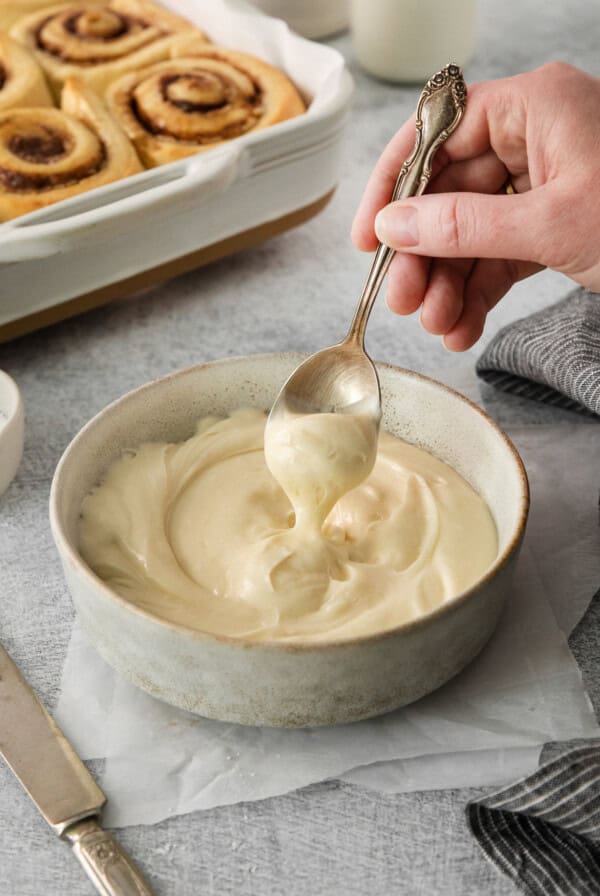 a person spoons a spoonful of cream in a bowl.