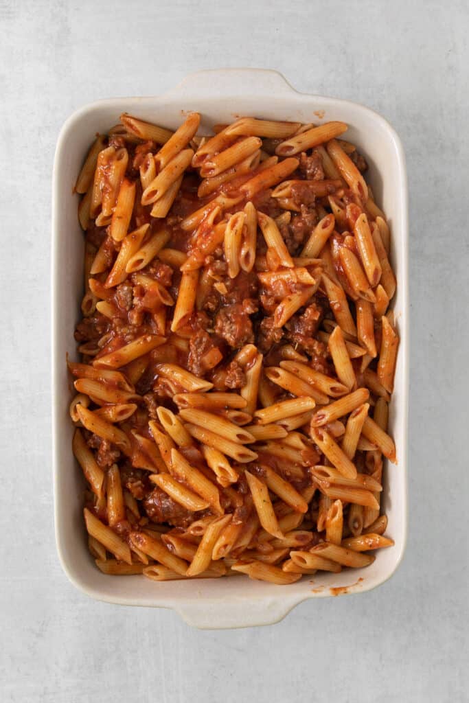 a white dish with pasta and meat in it.