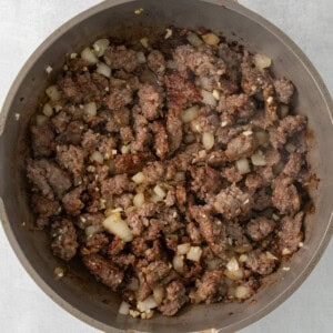 a skillet filled with ground beef and onions.