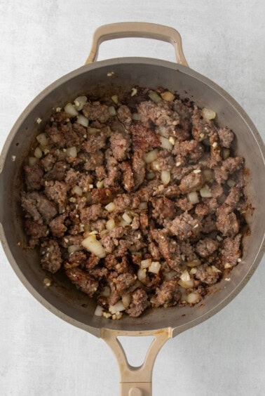 a skillet filled with ground beef and onions.