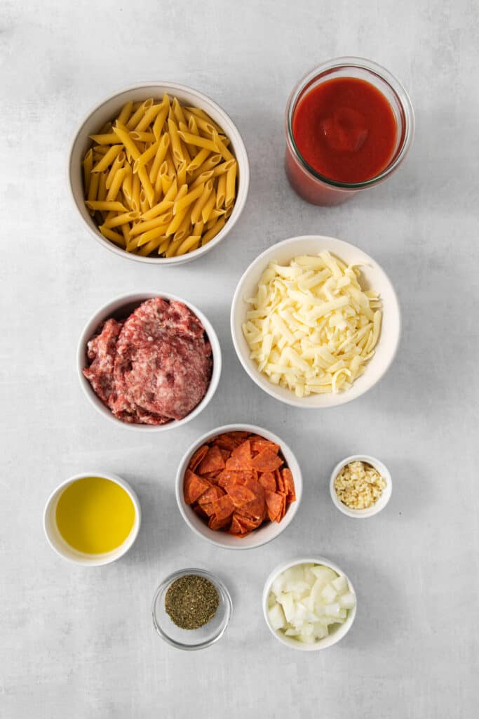 a bowl of pasta, meatballs, sauce and other ingredients on a white background.