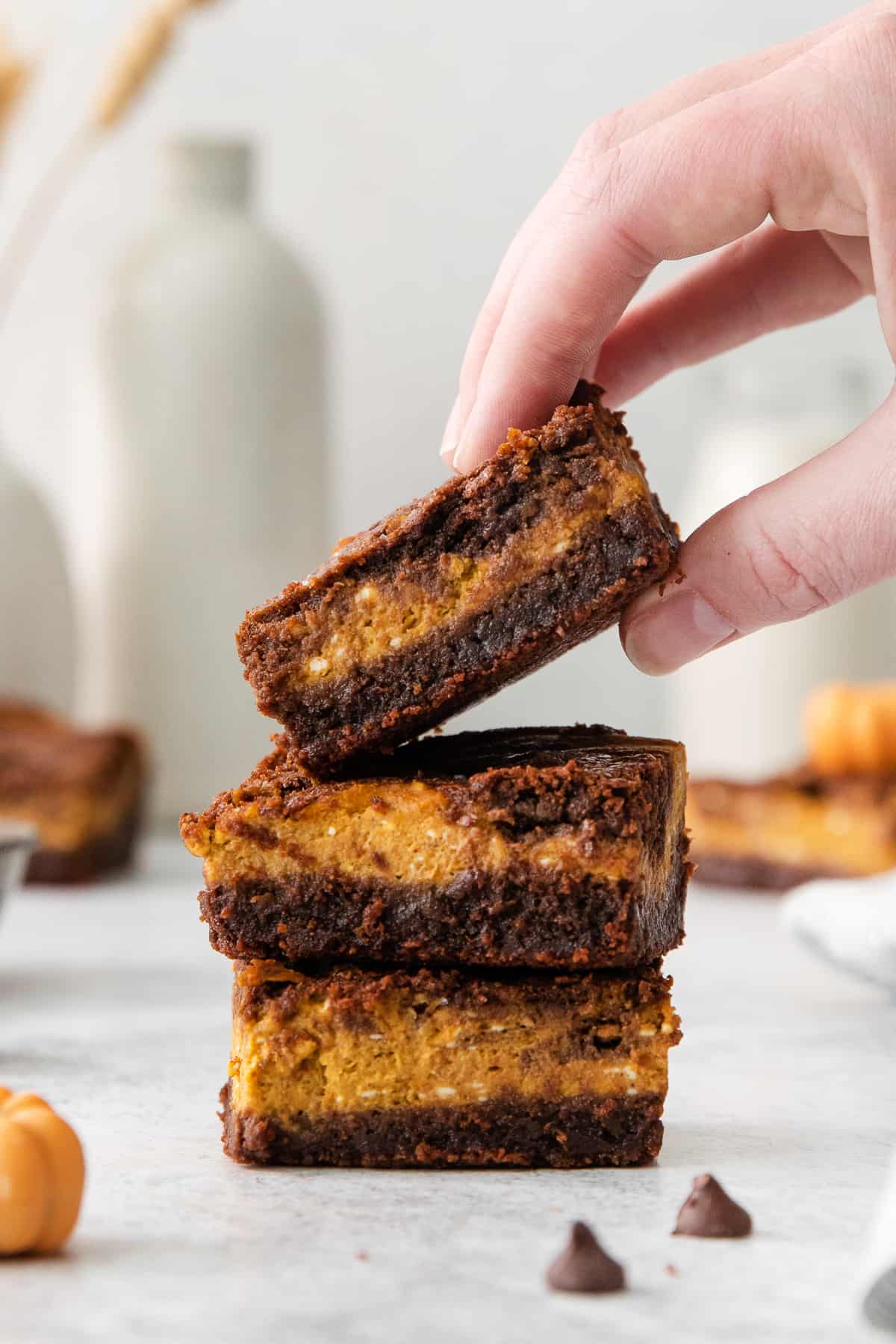 a hand grabbing a stack of pumpkin bars.