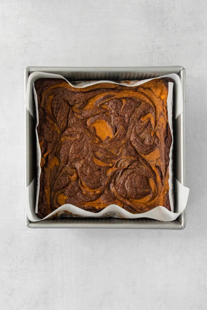 a brownie in a metal pan on a white surface.