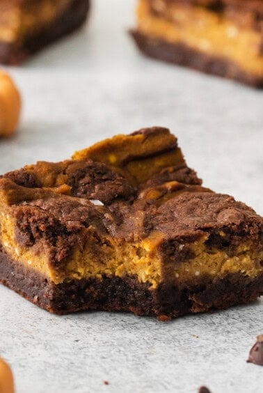 a slice of chocolate pumpkin brownies on a white background.